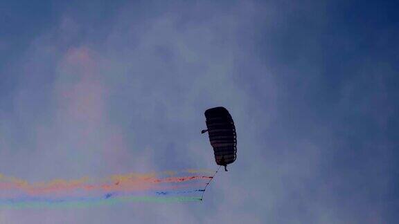 在一个阳光明媚的日子里跳伞者带着烟雾飞向天空