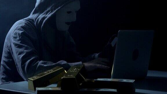 一名男子穿着连帽衬衫在黑暗中使用笔记本电脑入侵