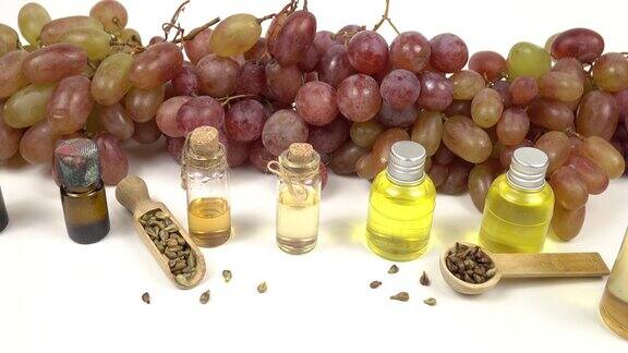 一套瓶子与葡萄籽油对粉红色葡萄束的背景