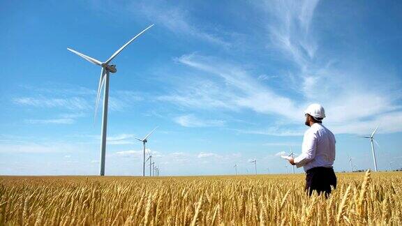 一个风力发电厂的工人在黄色的麦田里