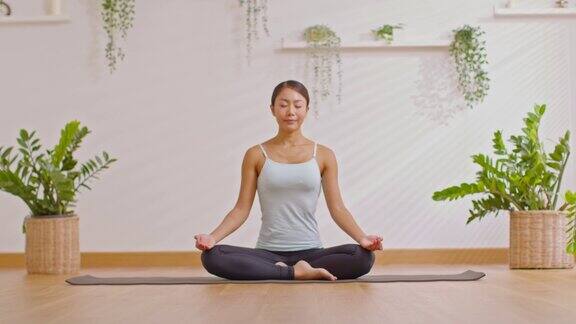 女子坐在瑜伽垫上做瑜伽莲花式呼吸瑜伽冥想