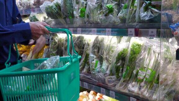 一个男人在超市购物一个男人挑选蔬菜做素食沙拉然后把它们放在篮子里