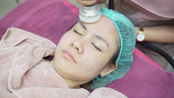 一名护士使用超声波机在一名亚洲妇女的脸上按摩在美容诊所医疗和美容皮肤科预约概念