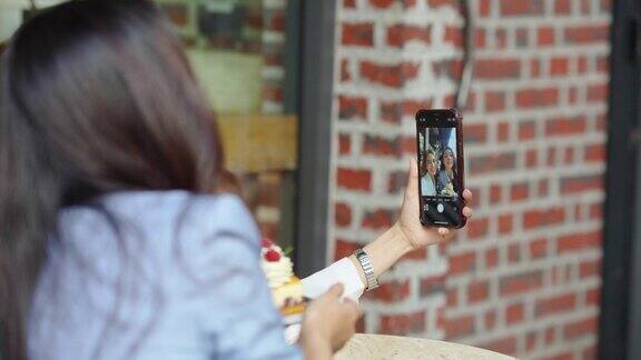 美丽的亚洲女性朋友在咖啡店用手机一起自拍
