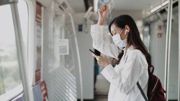 年轻女子戴着面具在火车上用手机社交慢镜头