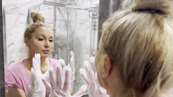 在浴室里用面膜照镜子的女人手部面膜