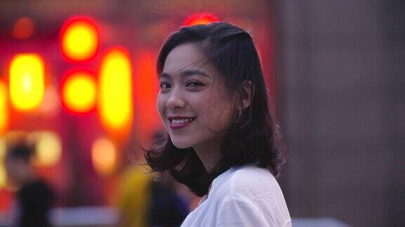 漂亮的亚洲年轻女子在晚上对着镜头微笑