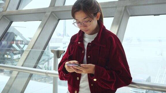 亚洲女性在国际机场使用智能手机查看航班信息等待登机