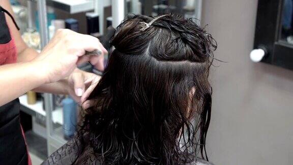 美发师在美容院剪黑发女孩她正在梳头和理发特写镜头4k