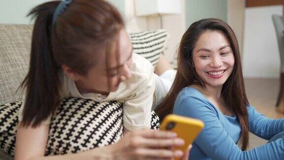 亚洲女性朋友一起在客厅用智能手机玩游戏
