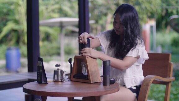 在后院餐桌旁的便携式咖啡机旁一名妇女正在煮咖啡
