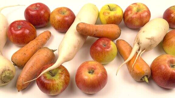 白色的桌子上放着萝卜、白萝卜、苹果和胡萝卜