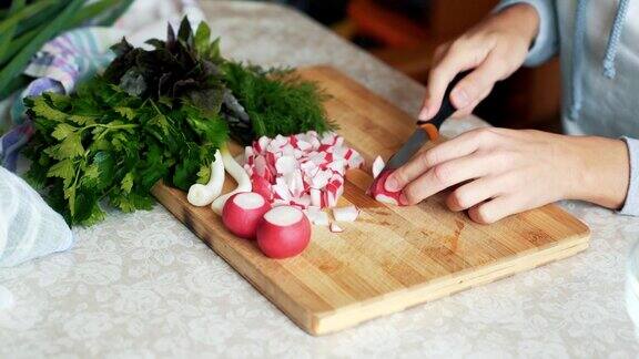 靠近女人的手用刀在木板上切萝卜概念的蔬菜