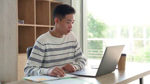 年轻的亚洲学生在家里用笔记本电脑打视频电话