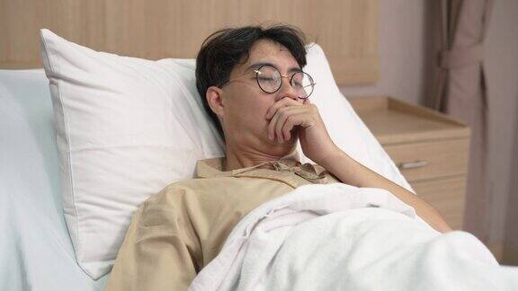 亚洲男性病人在医院休息时在床上感到不适