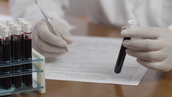 医生或化验员一手拿着化验室血液试管一手将结果写在病人的病历上