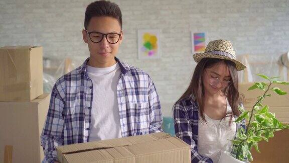 积极的年轻亚洲夫妇与箱子在他们的手搬进一个新的公寓和检查它