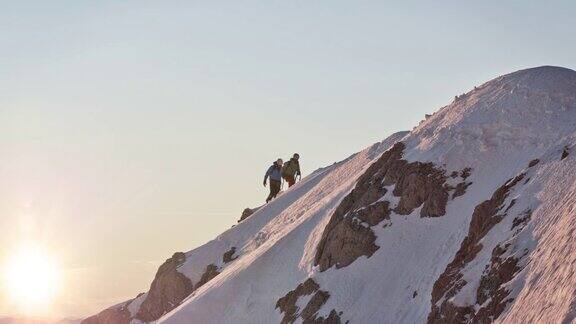 男性登山运动员在白雪覆盖的山脊上行走