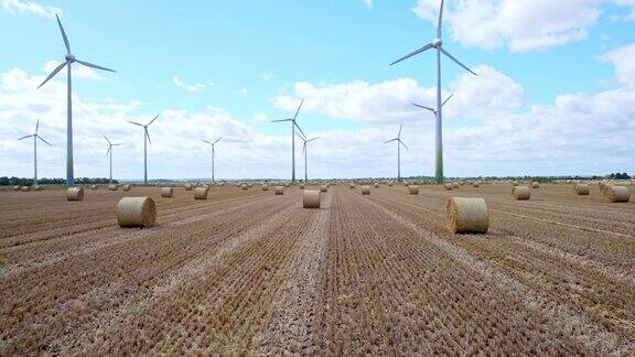 从上方拍摄一排风力涡轮机优雅地在林肯郡农民刚刚收割的田地上转动前景是金色的干草捆