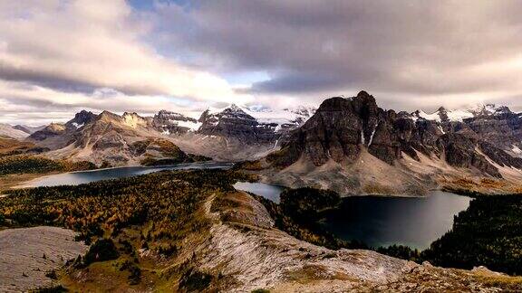 阿西尼博因山与云流动在Nublet峰与湖泊在省级公园日落