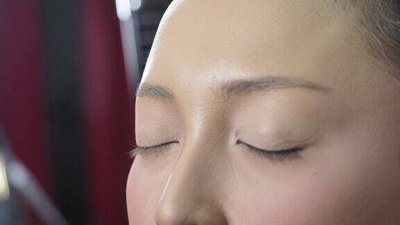 化妆师用化妆棉将粉底涂抹在眼睑周围