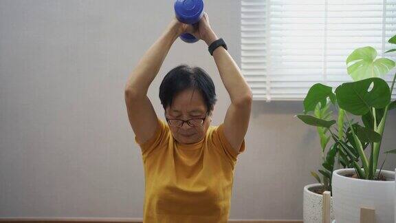 亚洲老年妇女在Covid-19隔离期间跟随在线教程和在家锻炼