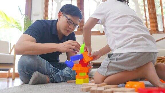 4K亚洲父亲和小女儿在家里玩积木玩具
