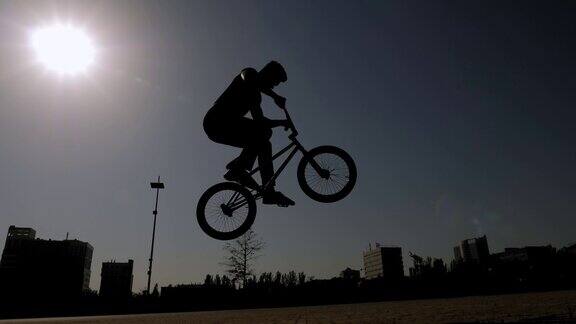 一个十几岁的男孩在城市公园里骑BMX自行车做特技的剪影