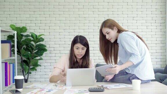 迷人、聪明、有创意的亚洲商务女性穿着时尚休闲装坐在办公桌上用笔记本电脑工作女性在办公室工作