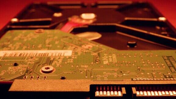 在红色灯光照射下的模糊背景上的硬盘驱动器芯片机构特写