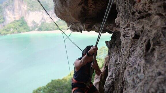 4K亚洲女人在夏天攀登热带岛屿的岩石山