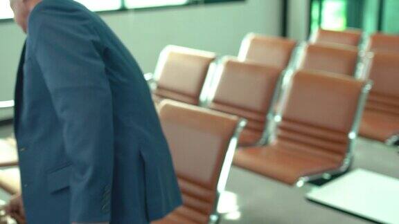 亚洲商人作为乘客用手推车携带行李然后坐在机场门口的等候椅上