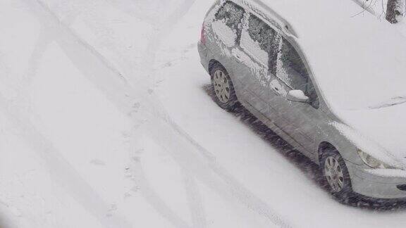 车在雪地里停在停车场雪地上的脚印暴雪冬日里飘落的雪花城市冬季背景