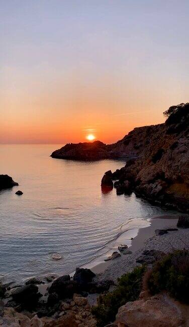 垂直景观的岩石卡拉萨拉达海滩与日落地平线在伊比沙岛西班牙