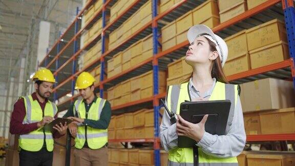 一位仓库女工正在检查仓库内的货物用平板电脑检查货架上的物品