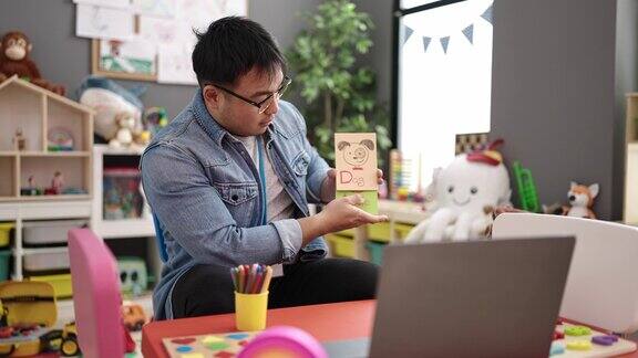 年轻的中国男子幼儿园老师正在幼儿园上在线词汇课