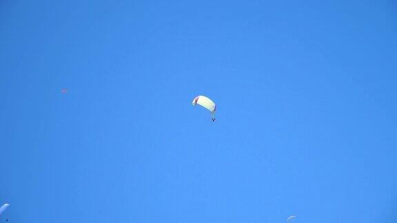 在阳光明媚的夏日里人们乘坐降落伞在气流中飞行享受夏日旅行早晨几架滑翔伞在湛蓝的天空中翱翔主动极限运动