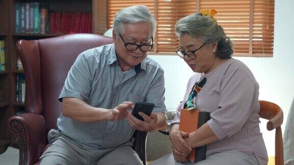 4K亚洲老夫妇一起在客厅里用智能手机