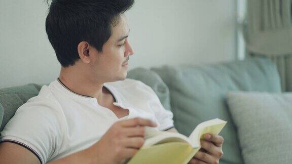 一个亚洲人正坐在客厅的沙发上看书