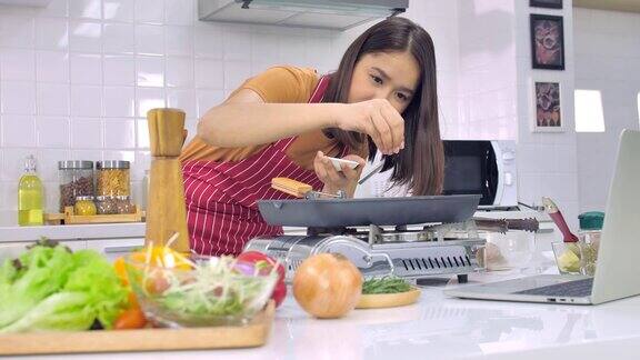 年轻的亚洲妇女在厨房做饭