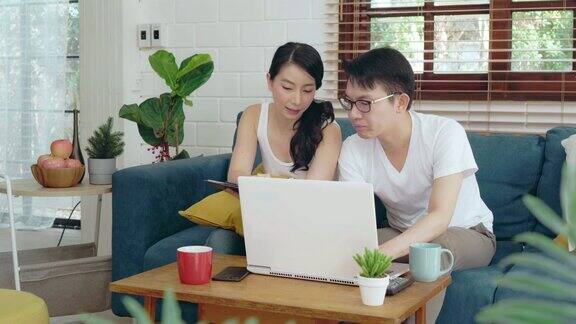亚洲夫妇家庭放松在沙发上工作的笔记本电脑商业财务