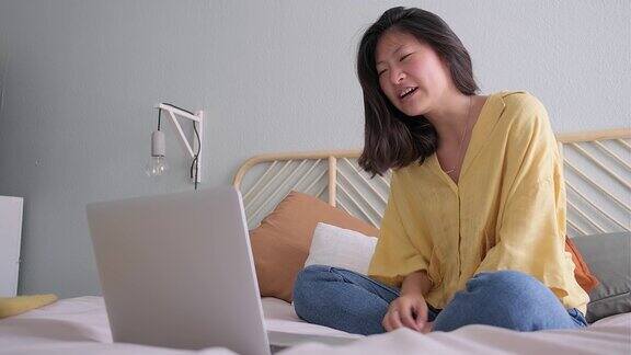 视频通话的年轻亚洲女性在网上上课中国少女对着笔记本电脑挥手4k决议