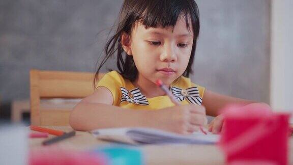 亚洲女孩坐在家里的客厅里学习和画画