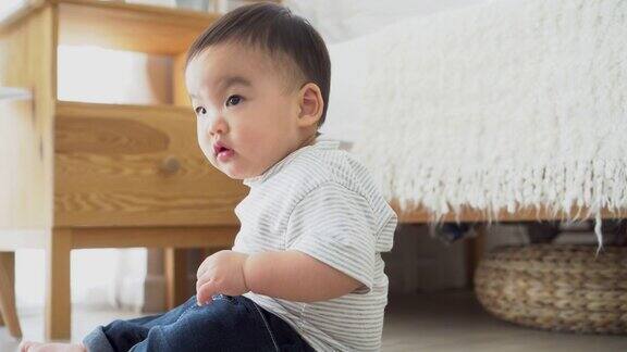 亚洲男孩独自坐在家里床边的地板上小孩呆在家里的客厅里