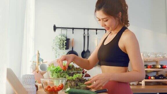 亚洲美女穿着运动服在厨房做蔬菜沙拉年轻漂亮的女孩心情愉快喜欢吃蔬菜健康饮食和减肥保健在家里