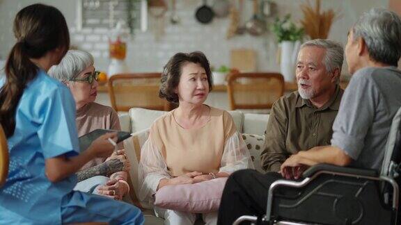 幸福快乐的老年男女与女性护理人员交谈护士医生在生活区进行健康检查咨询护理人员与老年夫妇坐在养老院的客厅