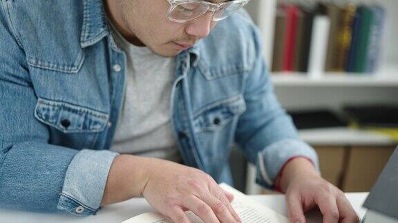 年轻的中国学生坐在图书馆的桌子上看书