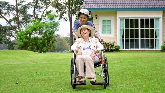 老妇人在后院和女儿坐在轮椅上休息