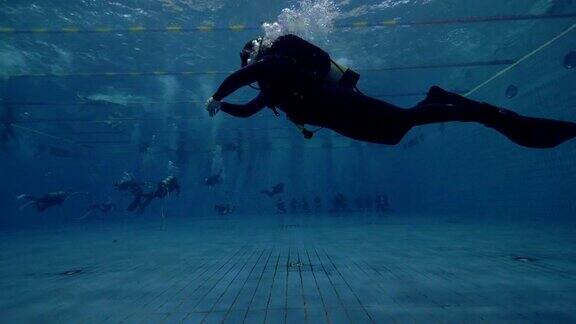 戴水肺的潜水员在游泳池的水下漂浮学习水肺潜水课程
