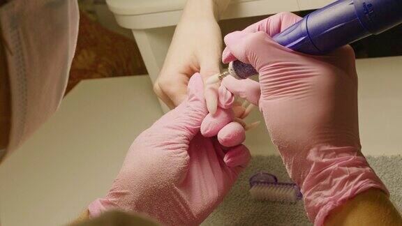 女美甲师正在给客户锯指甲护理美容指甲美容院美甲服务硬件修指甲去除材料掌握在美容院进行手套磨钉的程序